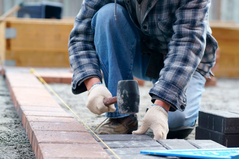 concrete worker installing concrete pavers